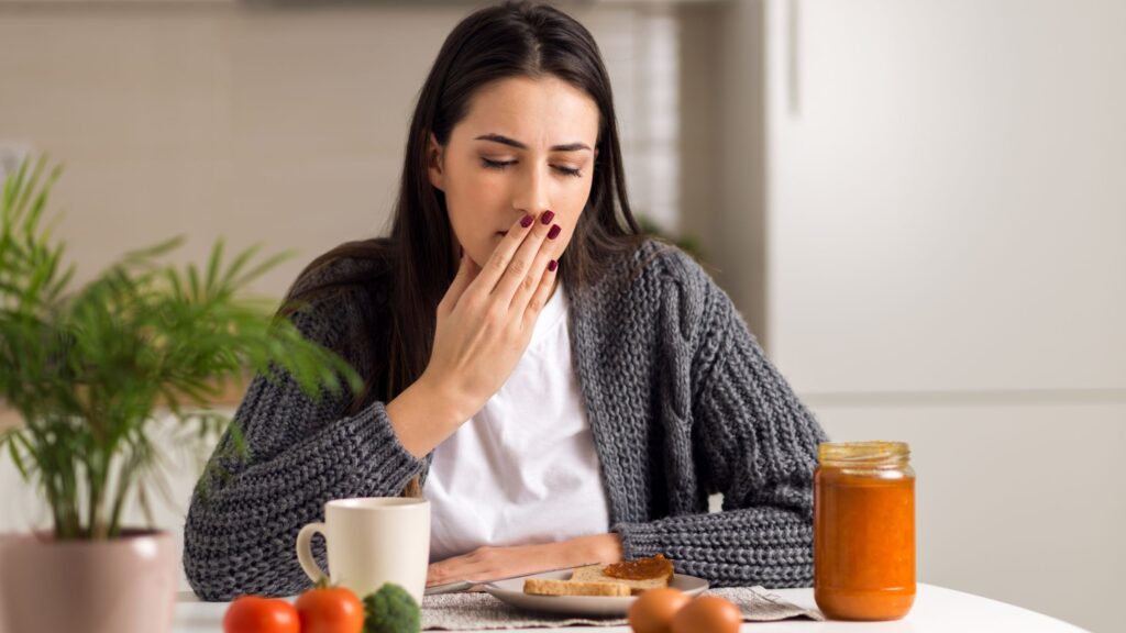 食事の前で口をおさえる女性